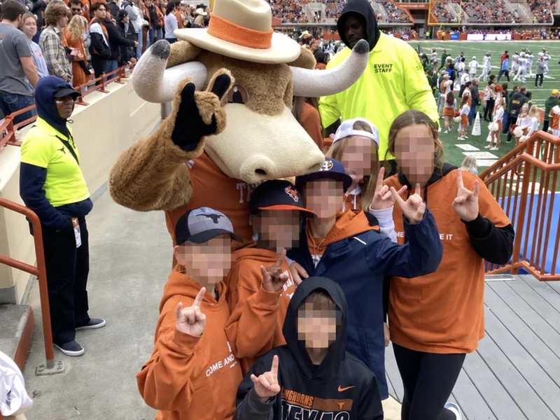 Children posing with Bevo at a Texas Longhorns football game; the children’s faces are obscured for privacy